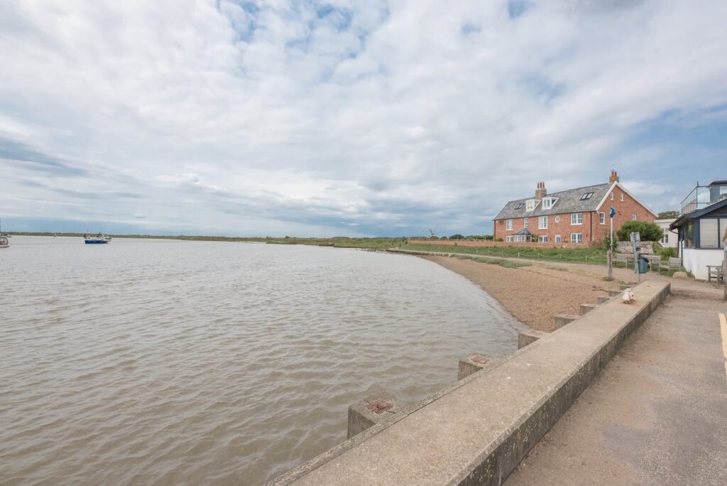 A large red brick house in the distance with a large body of water to its left