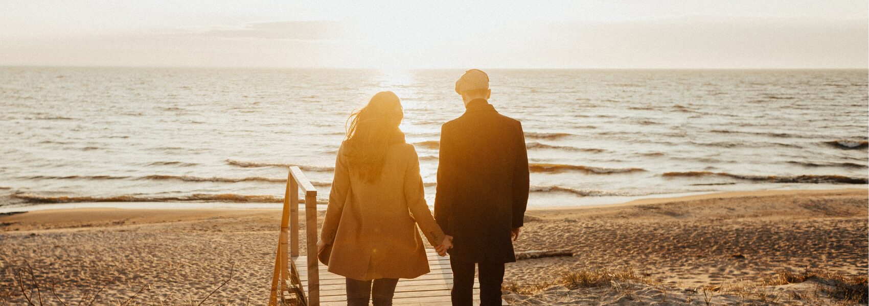 Couple walking holding hand on the beach in Suffolk